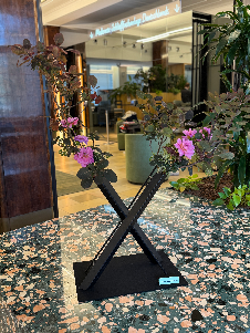 Blumen, Zweige, Blüten und Knospen kunstvoll arrangiert auf dem Gefäß mit dem Buchstaben X